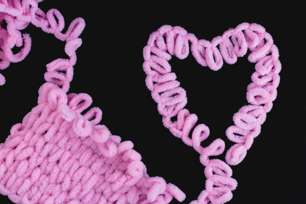 粉色纱线，用手指编织。Alize纱线。黑色背景。心图片下载