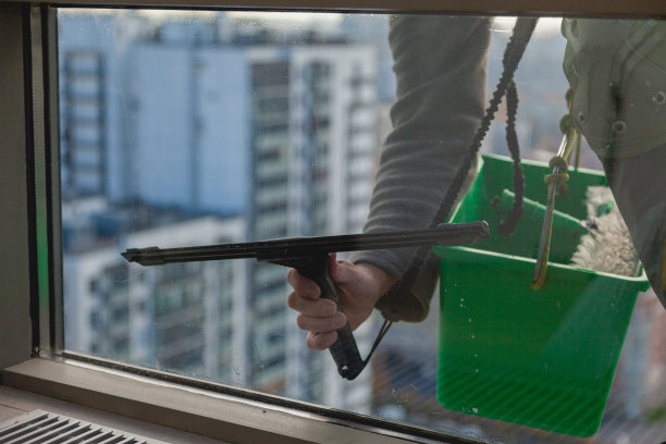擦高层建筑的窗户。铲斗和黏液的清洗过程借助于专业的工业攀爬器图片下载
