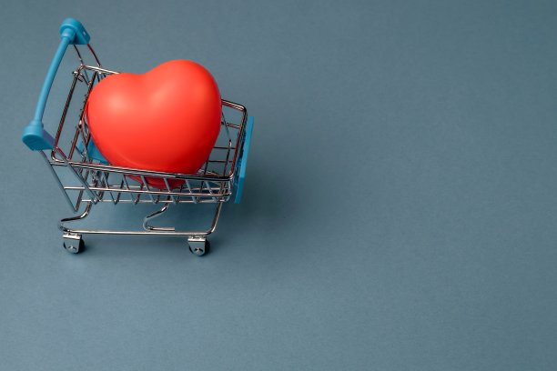 蓝色背景的购物手推车上的橡胶红心。图片下载