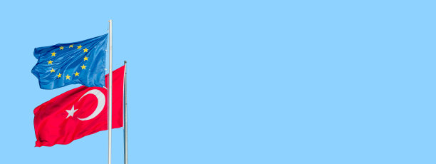 蓝色的旗帜与星星欧盟国旗和红色土耳其国旗与白色新月和星星吹在一个方向在蓝色的天空固体背景与复制空间。统一和团结的概念。图片下载