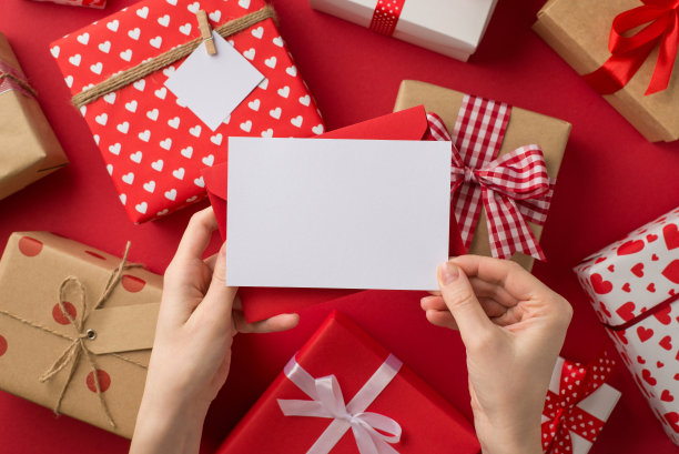 第一人称俯视图照片的情人节装饰女性手握红色信封和卡片在孤立的红色背景与空的空间礼物盒图片下载