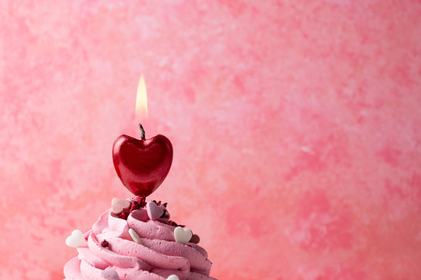 心形蜡烛在纸杯蛋糕上燃烧，情人节的概念。图片下载