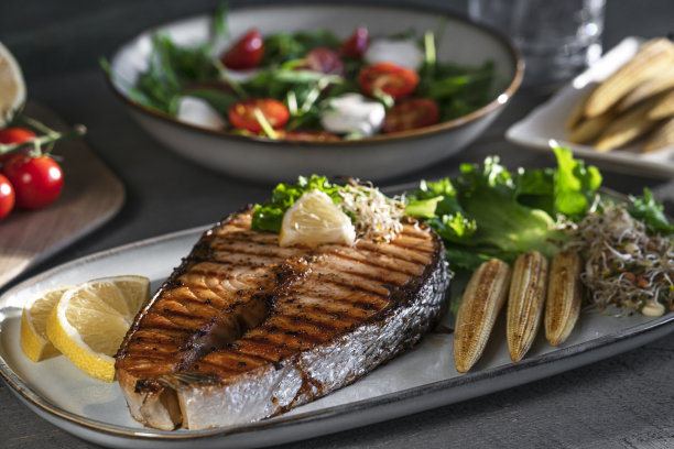 特写烤三文鱼牛排配迷你玉米、微绿色蔬菜、沙拉和柠檬图片下载