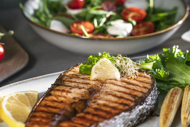 特写烤三文鱼牛排配迷你玉米、微绿色蔬菜、沙拉和柠檬图片下载