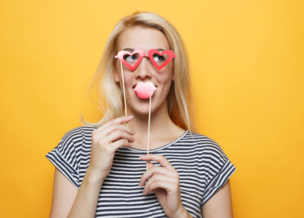 俏皮的年轻女子手持派对眼镜图片下载