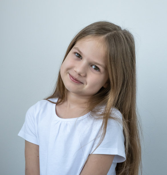 可爱的小白种人女孩在白色t短的灰色背景微笑的肖像。可爱的孩子看着镜头图片下载