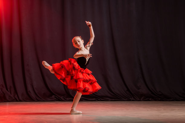 一个小芭蕾舞女演员穿着芭蕾舞裙，脚尖鞋和castanedas在舞台上跳舞，这是基特里的经典变化。图片下载