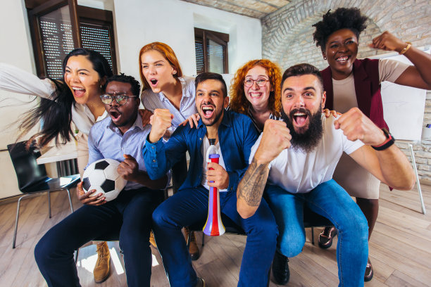 快乐的休闲商务人士或球迷在电视上观看足球比赛，庆祝胜利。友谊、体育和娱乐观念。图片下载