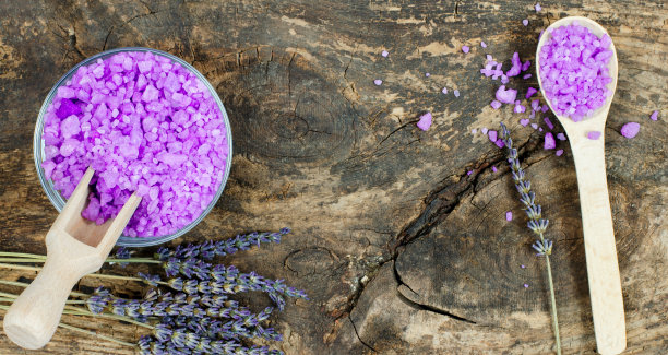 用海盐和薰衣草做化妆品广告的空白。海盐在一个碗和薰衣草花在一个木制背景与地方的文本。图片下载