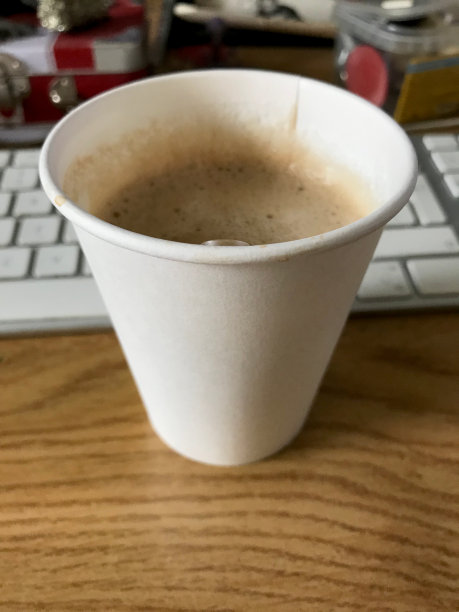 塑料杯与咖啡特写视图与模糊键盘的背景图片下载