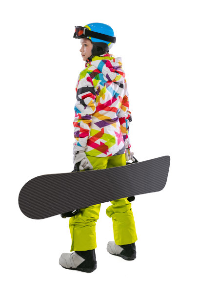 快乐的年轻女孩在明亮的运动服，护目镜和头盔站在滑雪板孤立的白色工作室背景。冬季运动的概念图片下载