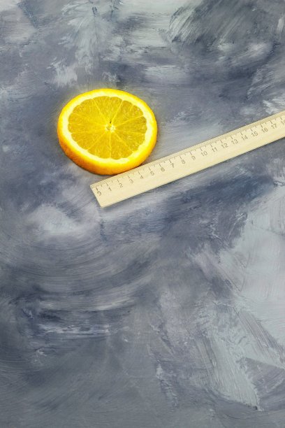 在这张垂直的照片中，是一把木制的学校尺子和一片多汁的橙子图片下载