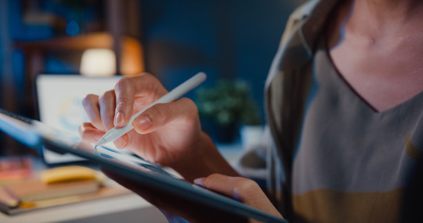 年轻的亚洲自由职业女性晚上在家里的客厅里使用平板电脑。在家工作的概念。图片下载