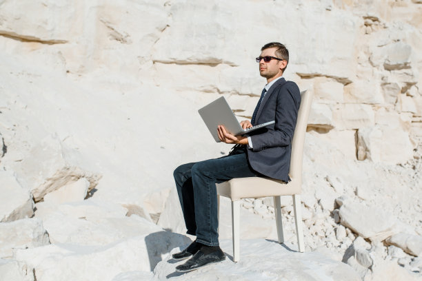 一个年轻的商人正在山里用电脑笔记本工作。图片下载