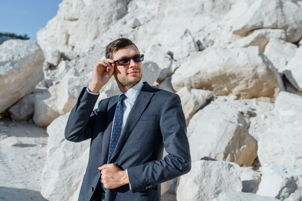 一个穿着古装、夹克、领带、戴着眼镜的男人在山上摆姿势。图片下载