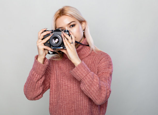 美丽的金发女人拿着灰色背景复制空间的老式相机图片下载