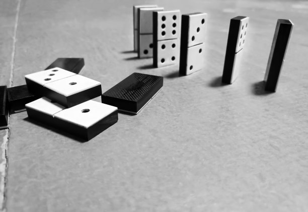 地板上的多米诺骨牌排成一排。石头旁边就躺着一张黑白照片。图片下载