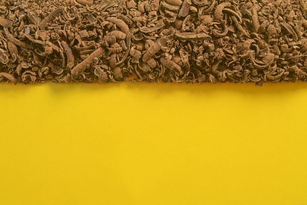 磨碎的巧克力口感。巧克力的背景。磨碎的黑巧克力。平铺和大的复制空间。黄色背景上的巧克力屑图片下载