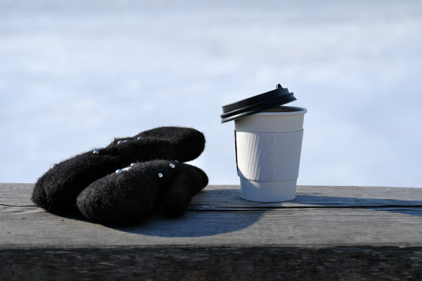 木凳上一个废弃的有黑色盖子的纸杯图片下载