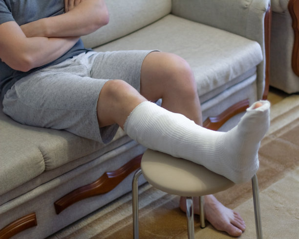那家伙打着石膏坐在沙发上。这条腿打了石膏。图片下载