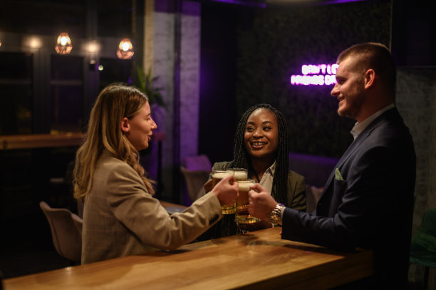 愉快的同事下班后一起在酒吧喝啤酒，用平板电脑图片下载