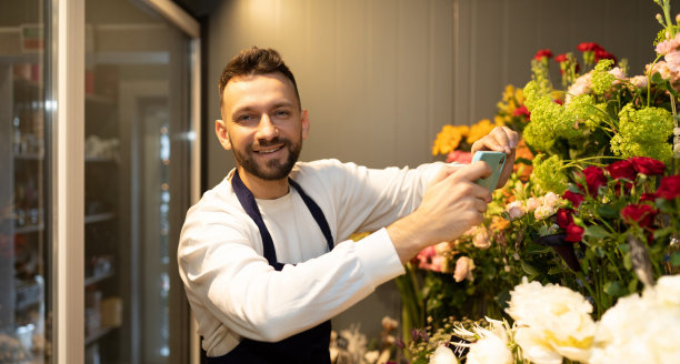 一位成功的企业家在自己的商店里拿着鲜花站在冰箱里，微笑着看着镜头图片下载