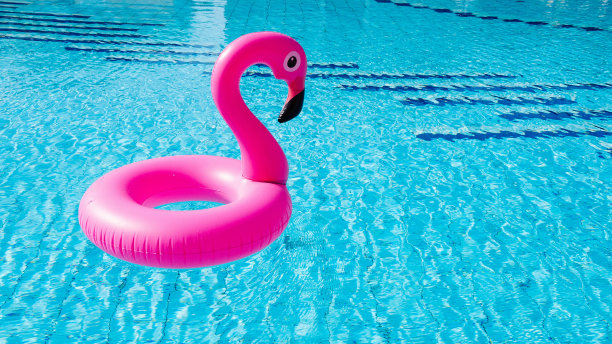 塑料火烈鸟。粉红色充气火烈鸟在泳池水为海滩背景。时尚的夏天的概念。图片下载