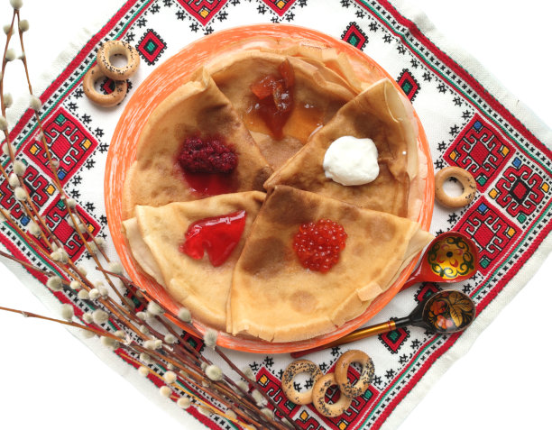 背景是薄煎饼，柳条，rushnyk和木勺孤立在白色的马斯伦尼萨节。图片下载