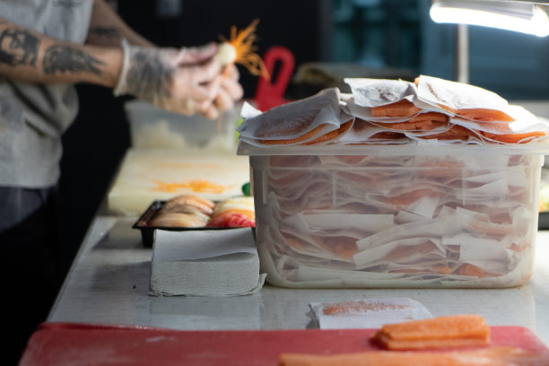 照片上有一块红色的木板，男性手里拿着一把刀，家里厨房里有一条红色的鱼。海鲜和食物图片下载