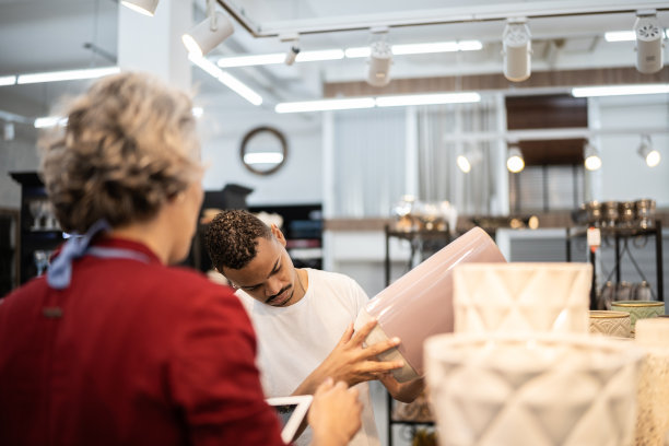 一名男子在家具店接受女售货员的帮助图片下载