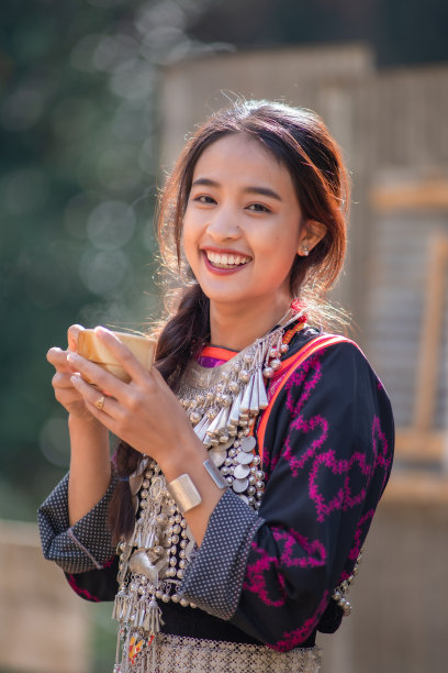 傈僳族女子端着一杯咖啡看着镜头。图片下载