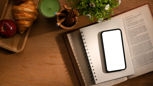 工作台，智能手机模型放在木桌上的一本书上。图片下载
