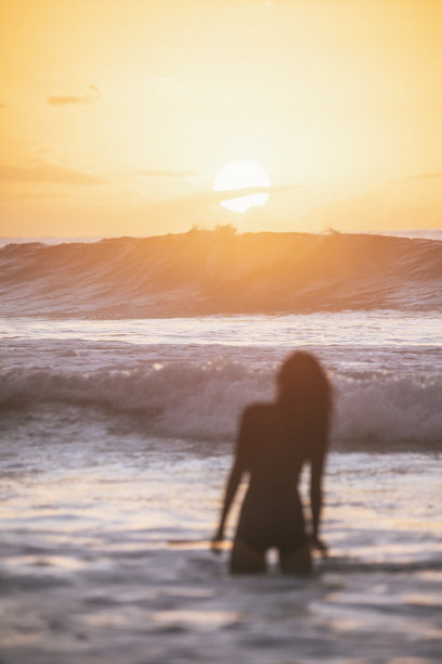 一个女人站在大海里，望着金色的夕阳图片下载