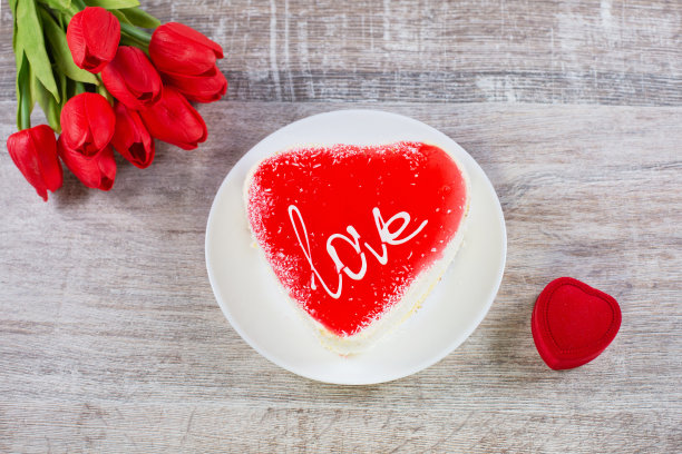 心形蛋糕、礼盒和木制背景上的鲜花。图片下载