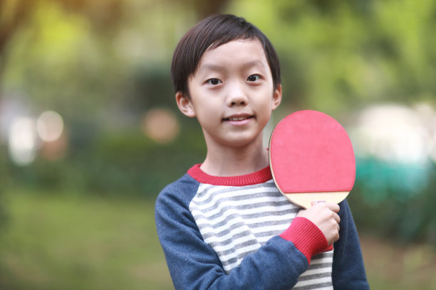 微笑的男孩在花园里打乒乓球图片下载