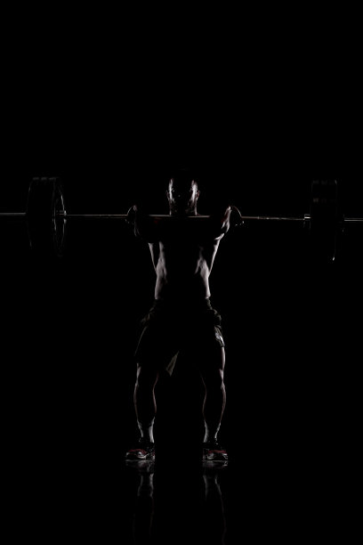 运动员举起杠铃。一个肌肉发达男人的剪影图片下载