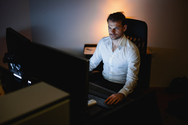 商人深夜在办公室用他的台式电脑图片下载