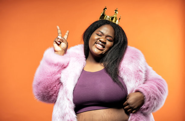 一个美丽的女人在彩色背景上穿着毛皮大衣摆姿势的照片图片下载