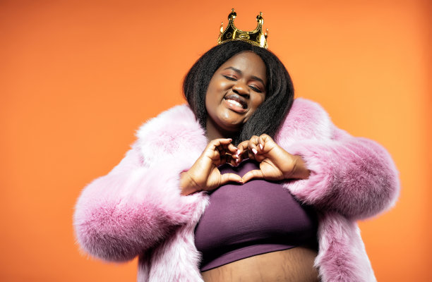 一个美丽的女人在彩色背景上穿着毛皮大衣摆姿势的照片图片下载