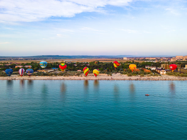 海滩上的热气球俯视图。气球从海边起飞的照片。一艘小船漂浮在热气球旁边的俯视图图片下载