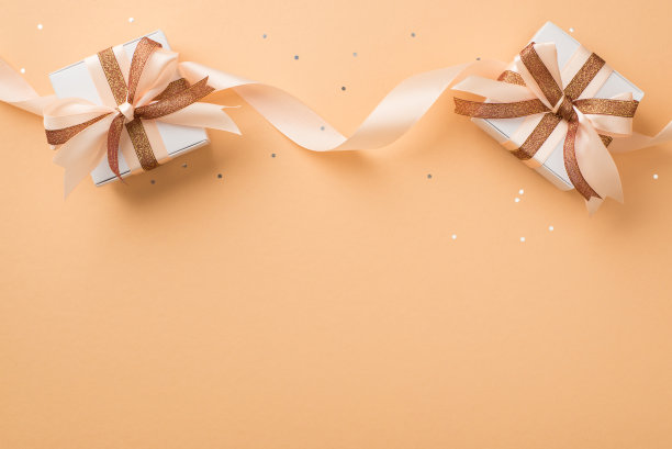 俯视图照片的情人节装饰白色礼品盒与发光的棕色和浅米色的卷曲丝带蝴蝶结和亮片在孤立的米色背景与空空间图片下载