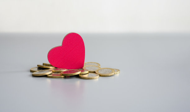 为有需要的人募捐。木制红心旁边的灰色背景上的硬币。图片下载