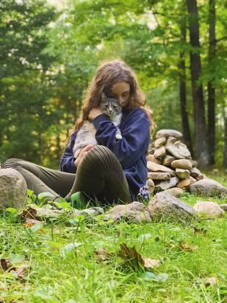 美丽的年轻少年拥抱她的猫，而坐在户外。图片下载