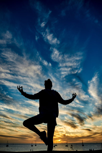 暑假期间，以海滩为背景进行冥想的快乐女人——关注女性剪影图片下载