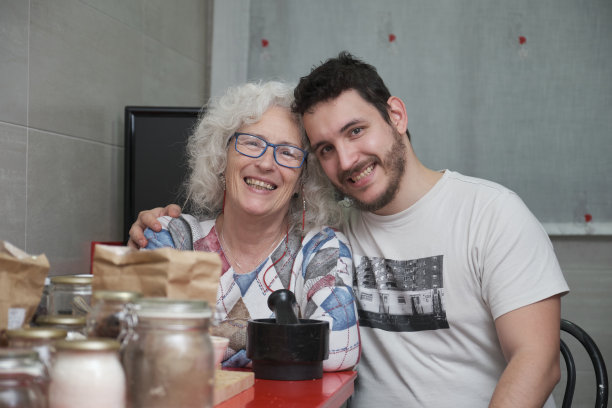 老母亲和成年儿子微笑着看着相机的照片。图片下载