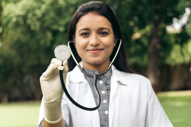 自信快乐的印度女医生向镜头展示听诊器并微笑的肖像。心脏检查，预防心脏病发作。医疗保健的概念图片下载