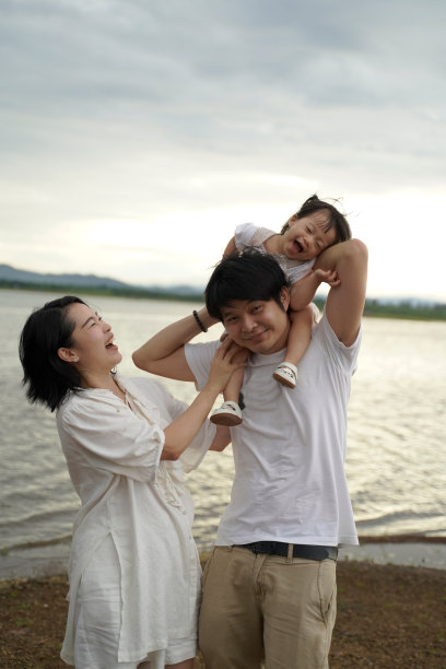 幸福的家庭有快乐的时间在一起，母亲，父亲，孩子的女儿在海滩在傍晚，日落。图片下载