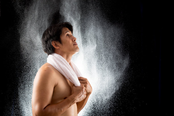 年轻的亚洲英俊的运动男子与白色毛巾握在飞溅的水滴图片下载