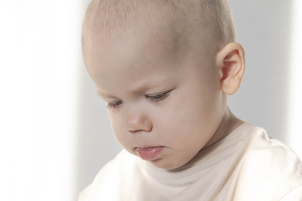 一个小男孩坐在床上的蓝色毯子上玩一部现代手机。图片下载