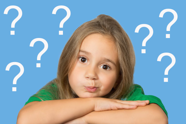 一个孩子，一个脸上带着沉思的表情的小女孩，在问号的背景下，把她的头放在交叉的双手上。一般教育理念。图片下载